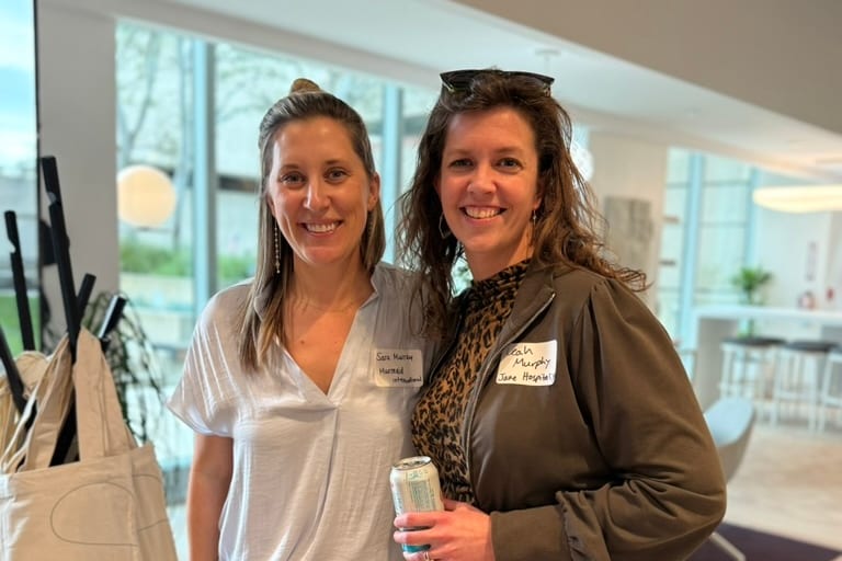 Two FFiH members smile together at a networking event