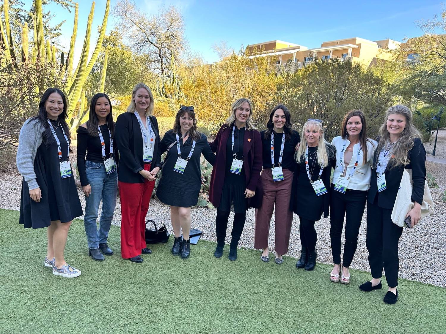 Nine FFiH members pose together outdoors in a desert garden at a conference