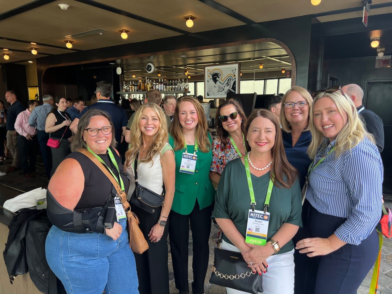 Seven FFiH members smile together at a rooftop bar during the HITEC conference